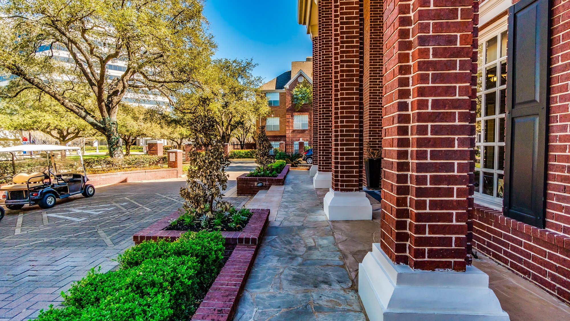 A brick building with a tree and a small garden in front.